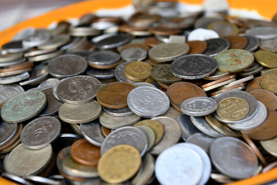 A close-up, shallow depth of field shot of a large pile of old vintage coins, including various denominations of Cypriot mils, shillings, and international currency collected together.