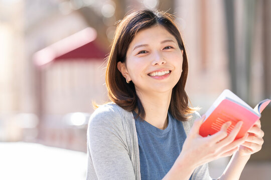 街の中で座って本を読んでいる女性