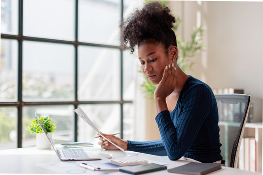 Woman carefully analyzing documents and financial data, calculating budget numbers, planning investments and making business decisions in a modern office workplace