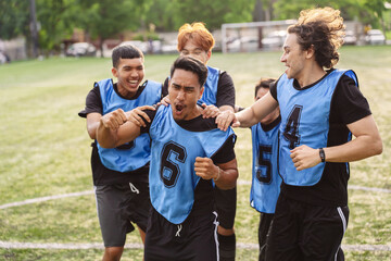 Fototapeta premium Excited soccer players cheering and running to celebrate a victory. Teamwork, passion, and success concept during a sports match on a turf field.