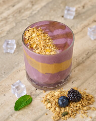 Purple berry smoothie with peanut butter swirl layer, topped with oats, granola, and honey drizzle. © GalastyX