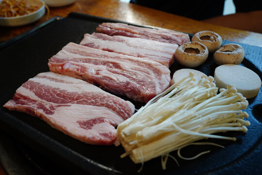 Traditional Korean barbecue K-BBQ fresh pork belly slices with enoki mushrooms