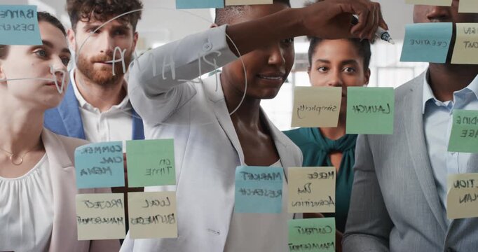 Woman, writing and team at office with notes, glass wall or planning at marketing company. Business people, talk or group with window, feedback or project management launch at advertising agency