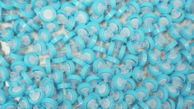 Laboratory technician handling blue PTFE syringe filters for sample purification before HPLC and LC analysis. Scientific research environment, chromatography sample preparation, analytical chemistry