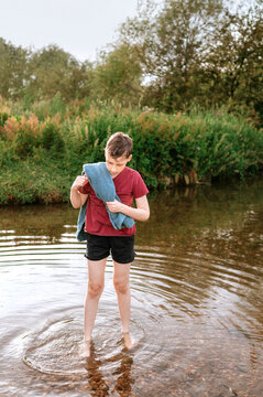 Boy drying himself with a shirt while standing in a stream