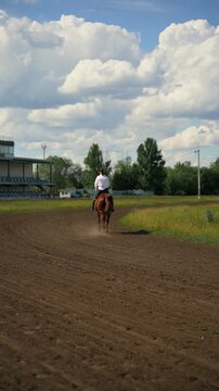 A woman riding a brown horse at the racetrack
