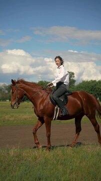 Woman riding a brown horse in a grassy field.