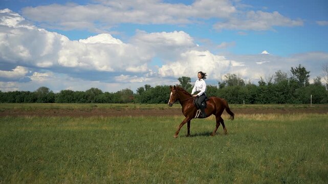 Woman riding a brown horse in a grassy field.