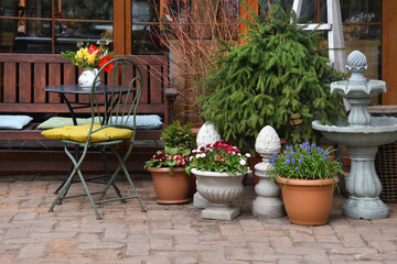 Fototapeta premium Cozy outdoor patio with bench, table, potted spring flowers and
