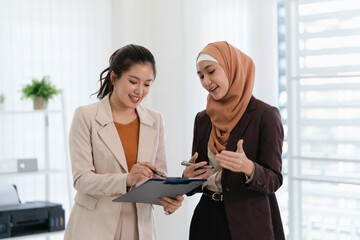 Obraz premium Two business colleagues multiethnic working in office, asian muslim