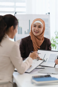 Two business colleagues multiethnic working in office, asian muslim