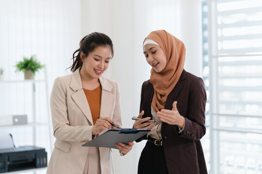 Two business colleagues multiethnic working in office, asian muslim