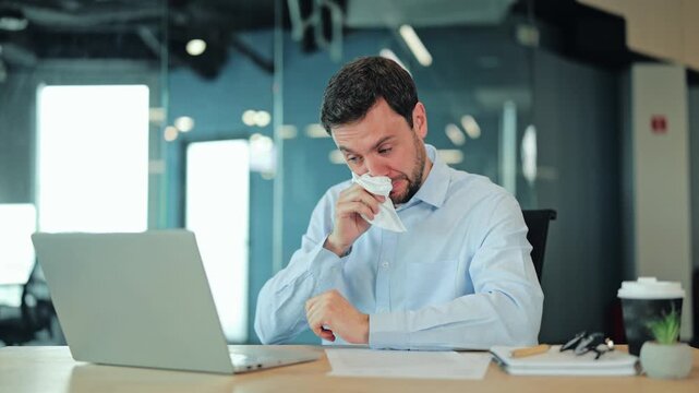 Close-up of unwell corporate manager or IT specialist suffering from runny nose, flu or allergy at laptop. Exhausted employee or freelance worker feeling severe cold symptoms and head ache at office
