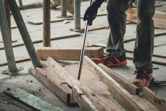 建設現場でバールを使用して型枠を解体する作業員の足元