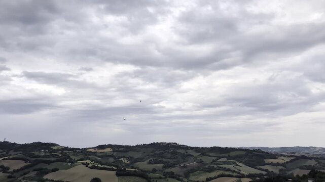 Panorama da Offagna con colline morbide, campi coltivati e cielo grigio compatto, per un&rsquo;atmosfera naturale e contemplativa tipica delle campagne italiane