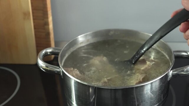 A woman cooks meat in her kitchen. Close-up of the pot on the induction stove.