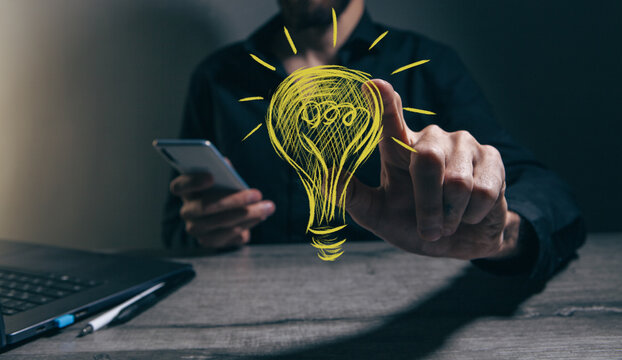 Businessman working with mobile phone and lightbulb drawing on screen