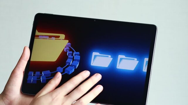 A hand reaches out to touch a tablet. The screen shows a digital folder surrounded by blue elements. This scene takes place indoors with natural lighting.