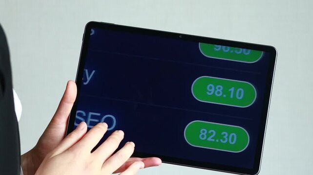 A person uses a tablet to check content optimization scores for meta tags, readability, and web page SEO. This takes place in a modern office during the daytime.