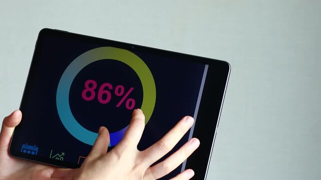 A person displays a digital tablet with a report showing the sales targets achieved at 86 percent. The setting is indoors with a plain background.