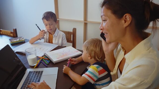 Young creative mother and her two little sons having fun painting with watercolors at home, engaging in a family artistic activity that promotes bonding and creativity for the children