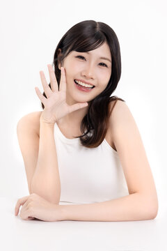 Portrait of beautiful Asian young woman with clean fresh skin and natural wavy hair, smiling and looking away, beauty skincare and haircare concept, isolated on white background.
