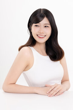 Portrait of beautiful Asian young woman with clean fresh skin and natural wavy hair, smiling and looking away, beauty skincare and haircare concept, isolated on white background.