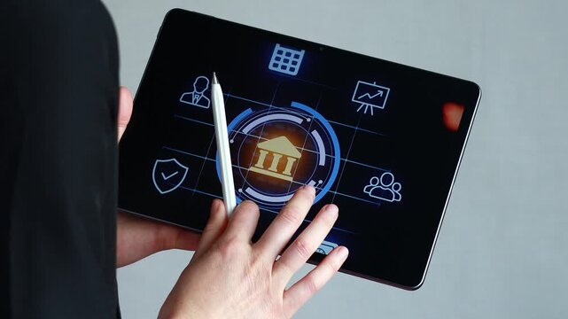 A person is using a tablet with banking icons displayed on the screen. The setting is an office with a focus on technology and finance. The activity involves digital interactions.