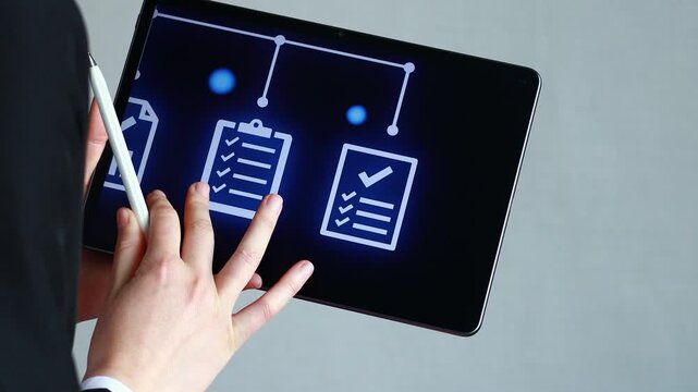 A person holds a tablet that displays a digital flowchart showing document organization. They are pointing to details with a stylus. This scene takes place in an office during the day.