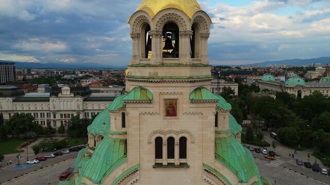 Detailed close aerial shot moving past the ornate stone arches and green copper rooftops of the Alexander Nevsky Cathedral bell tower in Sofia, Bulgaria