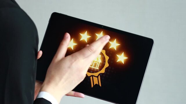 Holding a tablet with five stars and a badge design on the screen in a bright indoor setting during daytime.
