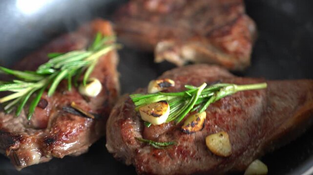 Close-up of delicious cooked steaks. Steaks being cooked with sprigs of rosemary and garlic.