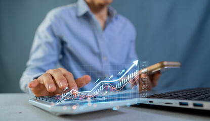 Fototapeta premium Businessman using laptop and smartphone with growing stock market graph for financial investment
