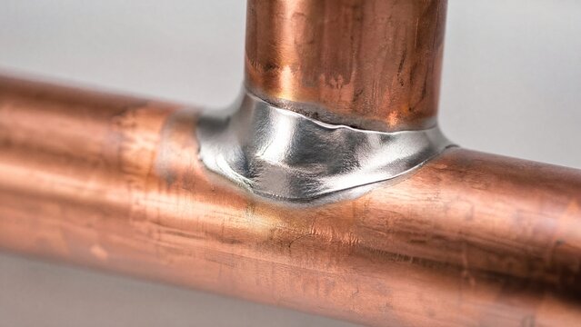 brazed. Close-up detail of brazed copper pipe joint with smooth gleaming solder fillet. event key visuals, club posters, designed for sports event promotions and stadium branding, supports training.
