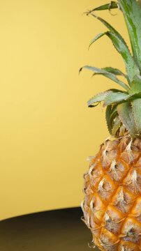 Vertical ripe pineapple rotating with copy space on yellow background
