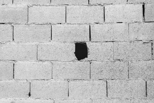 Concrete block wall with hole, unfinished construction background texture