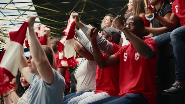 Excited football supporters celebrating with confetti in stadium stands, waving red scarves and cheering during live soccer match victory and team spirit, ecstatic supporters celebrate champions team.