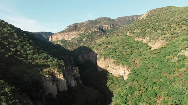 Backward aerial view of steep canyon walls and green mountains at sunset in Sierra P&eacute;njamo, La Garita Canyon, Mexico