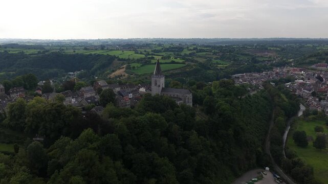 Spectacular aerial view flying away from the historic city of thuin in belgium, revealing the belfry, the sambre river, and the picturesque walloon countryside on a cloudy day