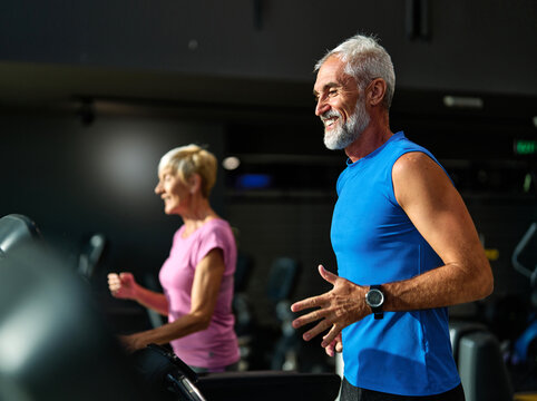 Portrait of a senior man exercising in a gym, mature couple running using threadmill machine equipment, healthy lifestyle and cardio exercise at fitness club concepts, vitality and active senior, coac