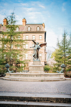 Historic bronze angel monument before elegant city mansion and park