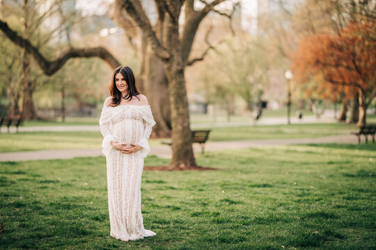 Pregnant woman embracing belly in park maternity
