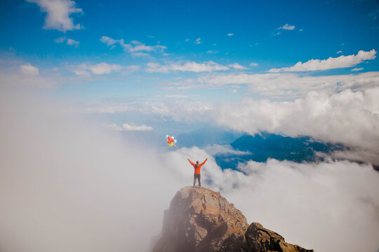 Hiker celebrates on a mountaintop with balloons