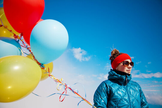Woman with balloons celebrating on a sunny winter day
