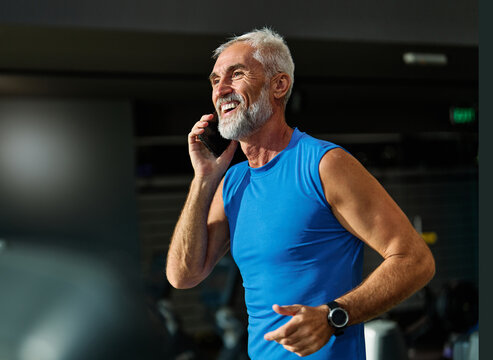 Portrait of a mature mid aged man using a phone and making a selfie photo, taking a break exercising in a gym, running using thereadmill machine equipment, healthy lifestyle and cardio exercise at fit