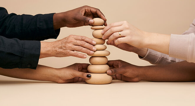 Diverse women's hands building a wooden tower together, symbolizing female empowerment, unity and collaboration.
