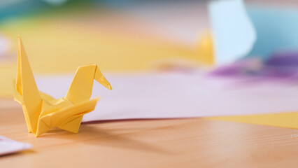 Yellow Origami Paper Crane on a Wooden Crafting Table