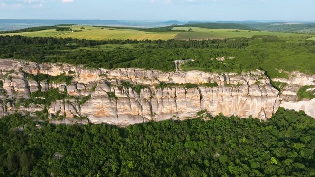 Madara Rocks limestone cliff aerial Bulgaria drone panorama green forest plateau UNESCO heritage nature landscape slow motion Balkans scenic summer overview wide rocky escarpment travel