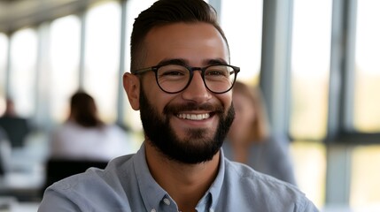 Obraz premium A smiling professional man in a casual shirt is captured in a bright office setting under natural daylight