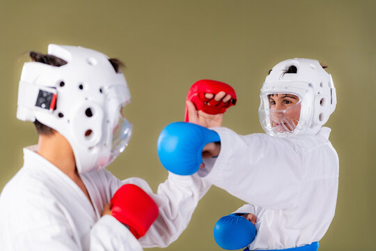 Karate fighter extends a straight red gloved punch toward the opponent's face while the defender counters with a simultaneous strike